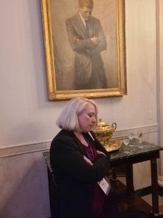 Teacher posing in front of portrait of JFK 